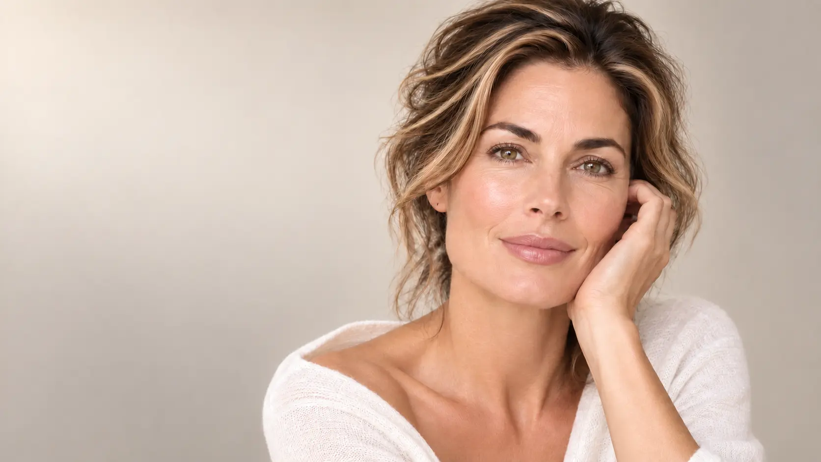 Mature woman with naturally luminous skin and softly highlighted brunette hair